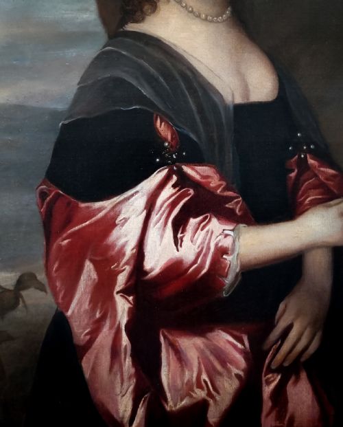 fig 3. A seventeenth-century oil portrait of a lady in a black dress with draped red satin sleeves and pearls, set within an ornate carved gilt frame.