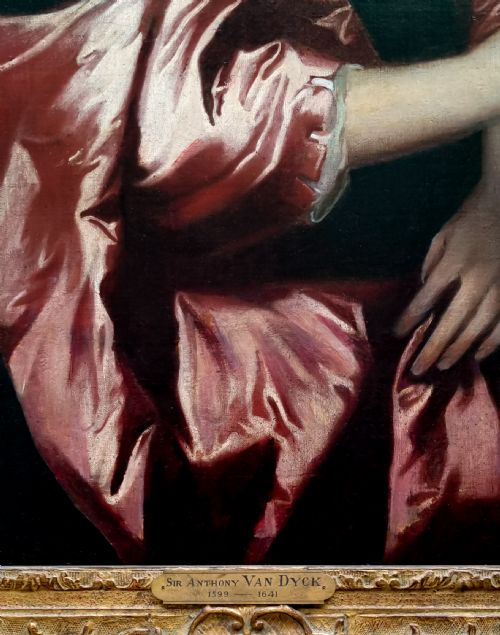 fig 4. A seventeenth-century oil portrait of a lady in a black dress with draped red satin sleeves and pearls, set within an ornate carved gilt frame.