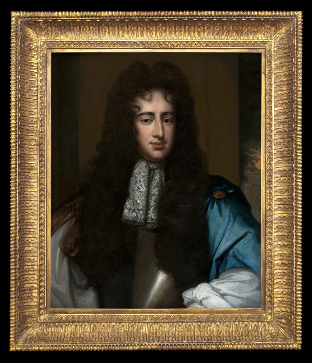 An oil portrait depicting a gentleman in a long dark wig, lace cravat, and blue cloak, presented within an ornate carved giltwood frame.