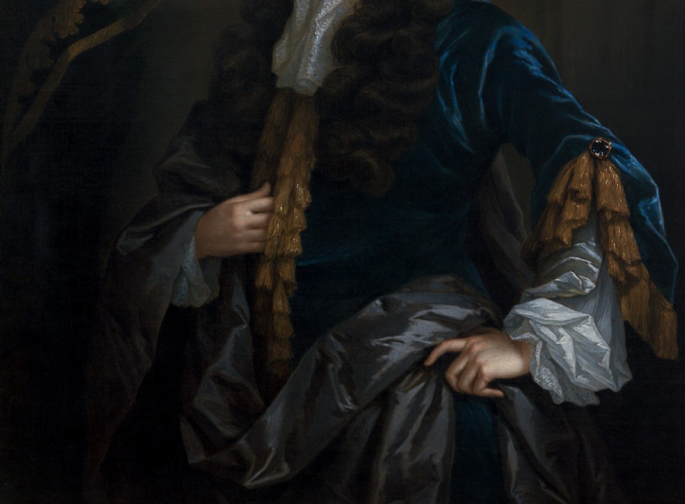An oil painting of a 17th-century gentleman wearing a dark blue coat, full brown wig, and white lace cravat, set inside an ornate carved gilded frame. View VI