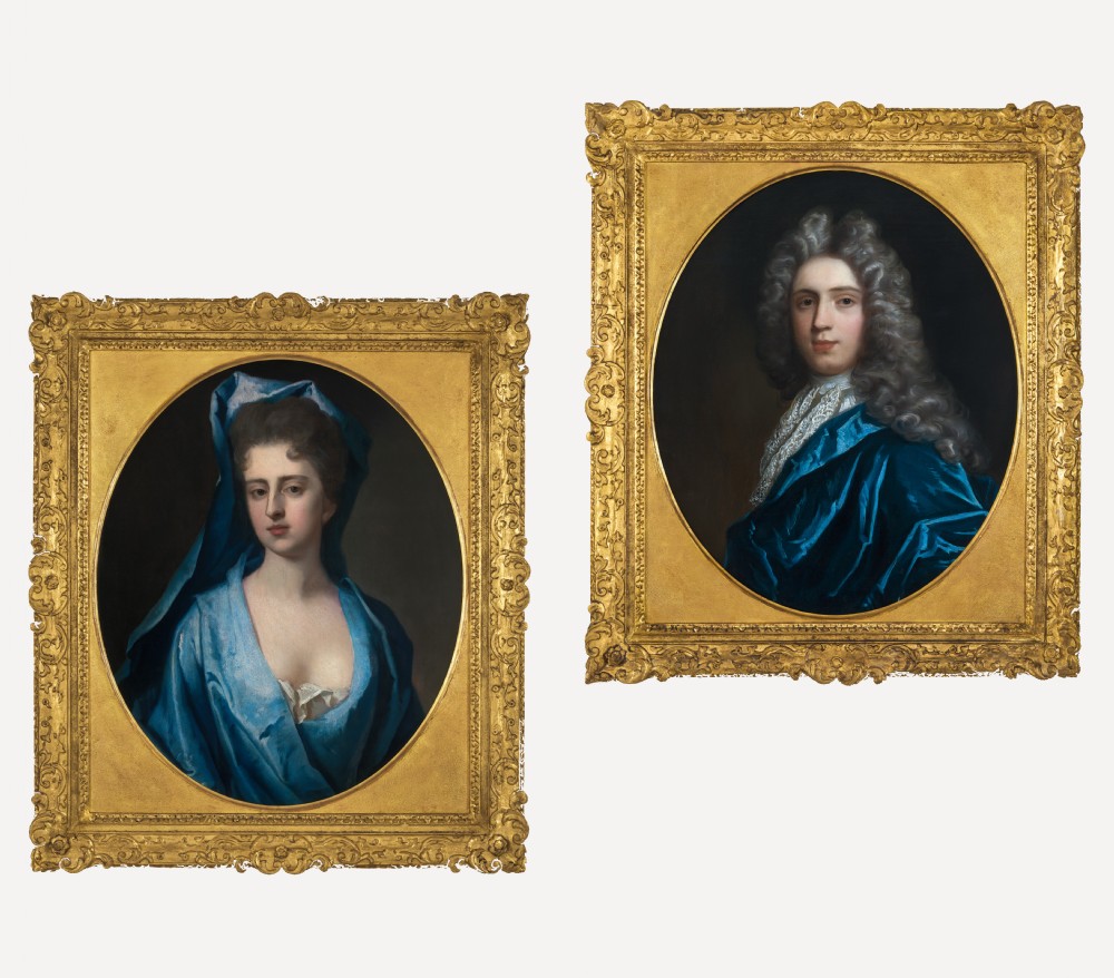 Pair of early eighteenth-century oil portraits on canvas featuring a man and a woman in blue drapery framed in elaborate carved gold giltwood frames.