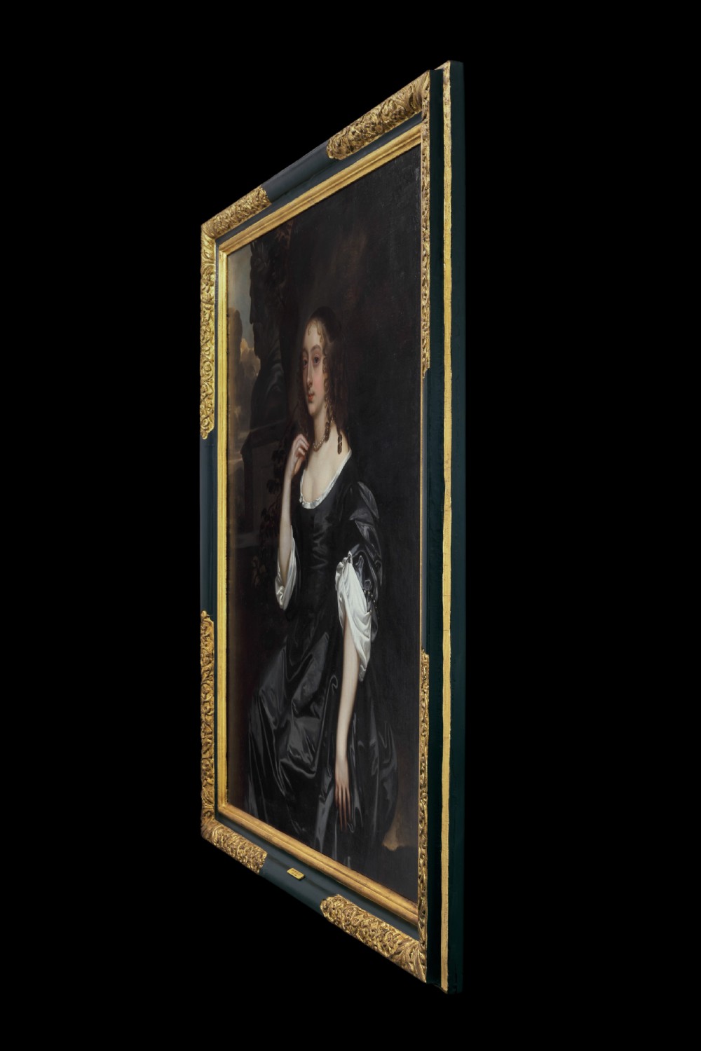 An oil painting depicting a 17th-century woman in a black dress with white satin sleeves and a pearl necklace, set against a dark backdrop with a stone bust sculpture inside a dark frame with gilded corners. View II