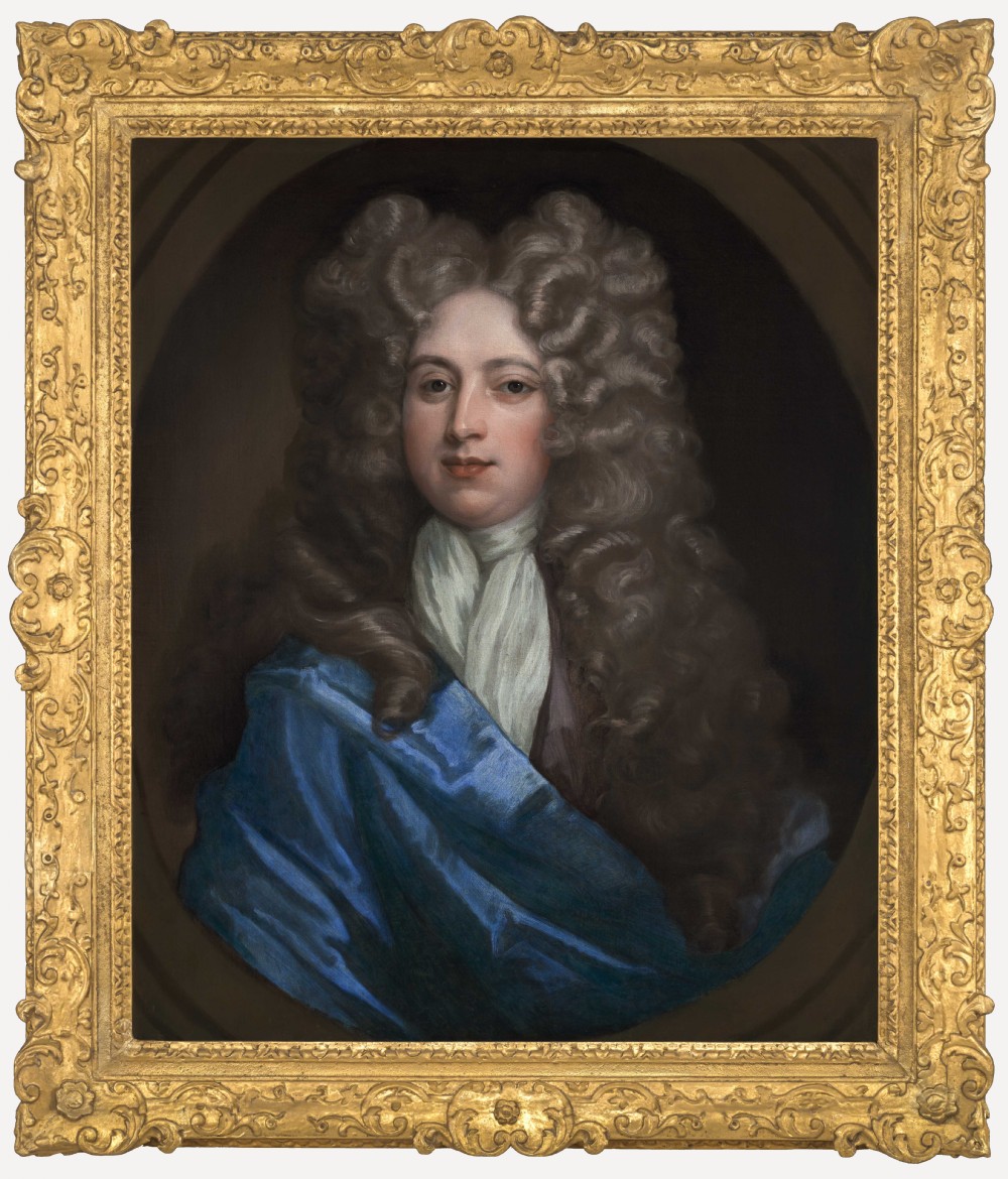 An oil on canvas portrait depicting a gentleman in a full brown periwig and draped blue cloak set within an oval spandrel and carved gold frame.