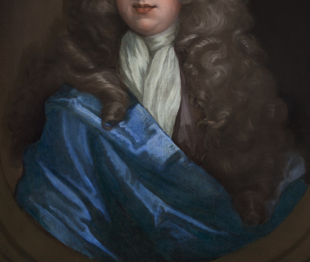 An oil on canvas portrait depicting a gentleman in a full brown periwig and draped blue cloak set within an oval spandrel and carved gold frame. View VI