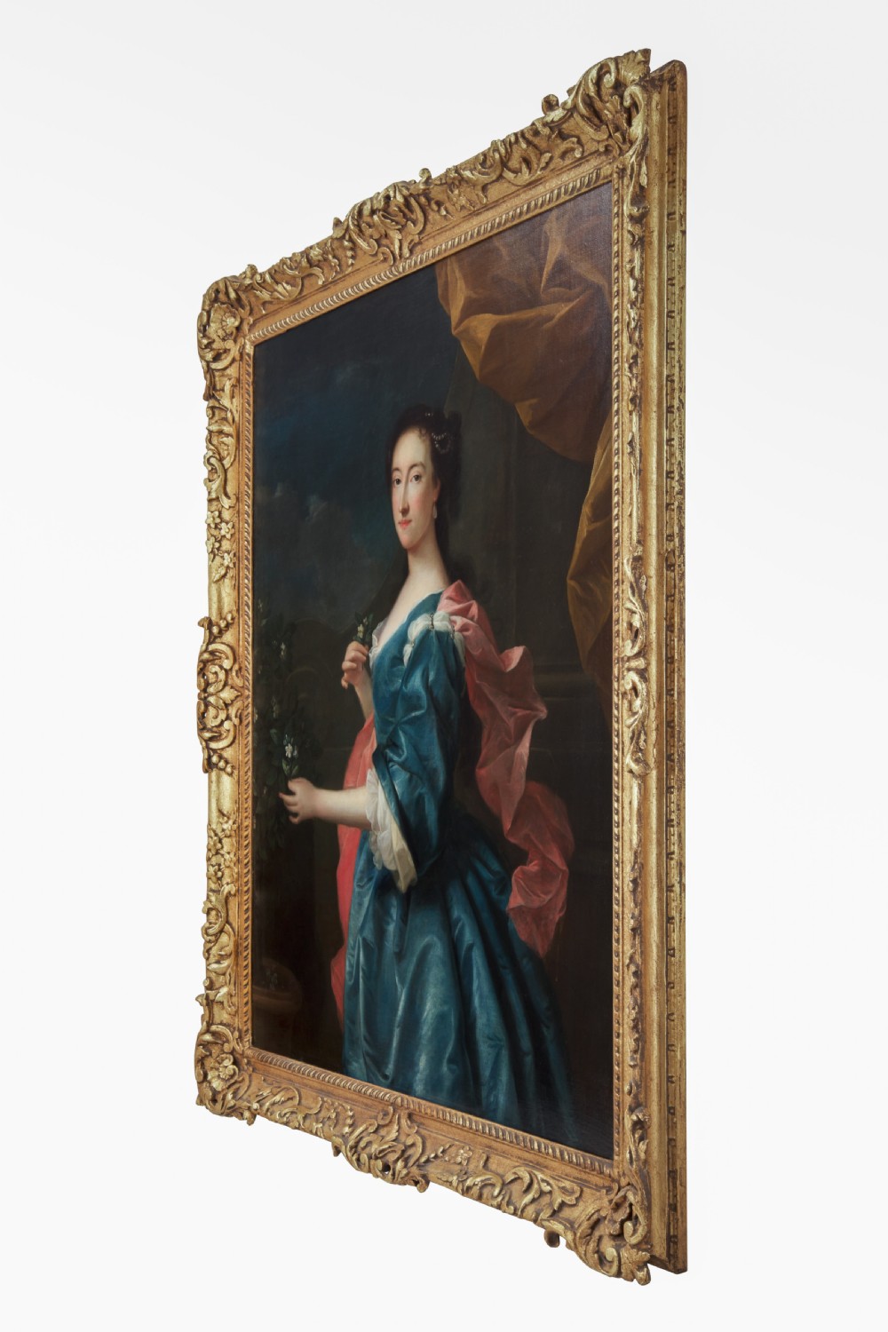 An 18th-century oil painting depicting a woman in a blue satin dress beside a potted orange tree, framed in carved giltwood. View III