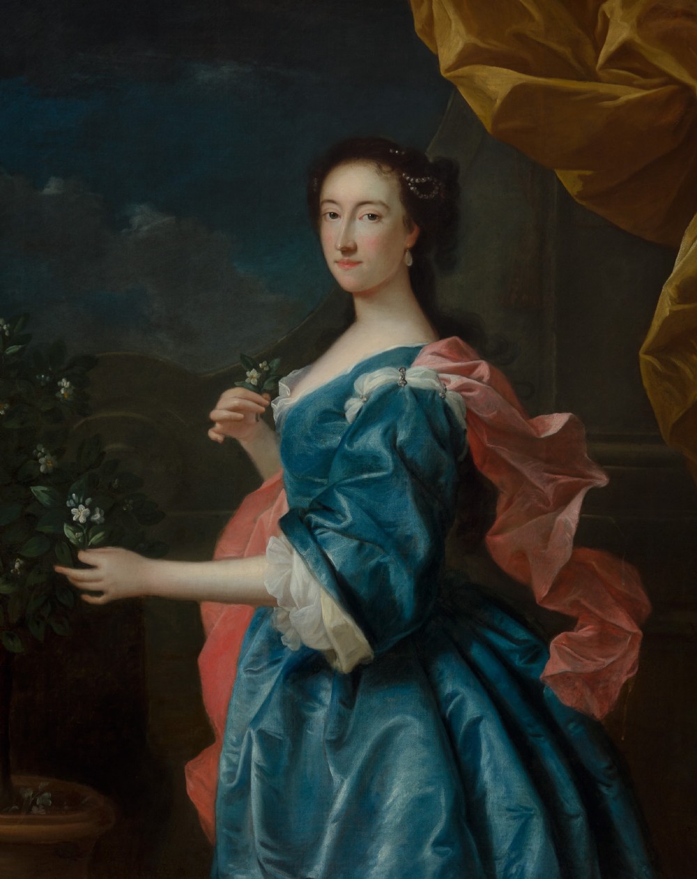 An 18th-century oil painting depicting a woman in a blue satin dress beside a potted orange tree, framed in carved giltwood. View V
