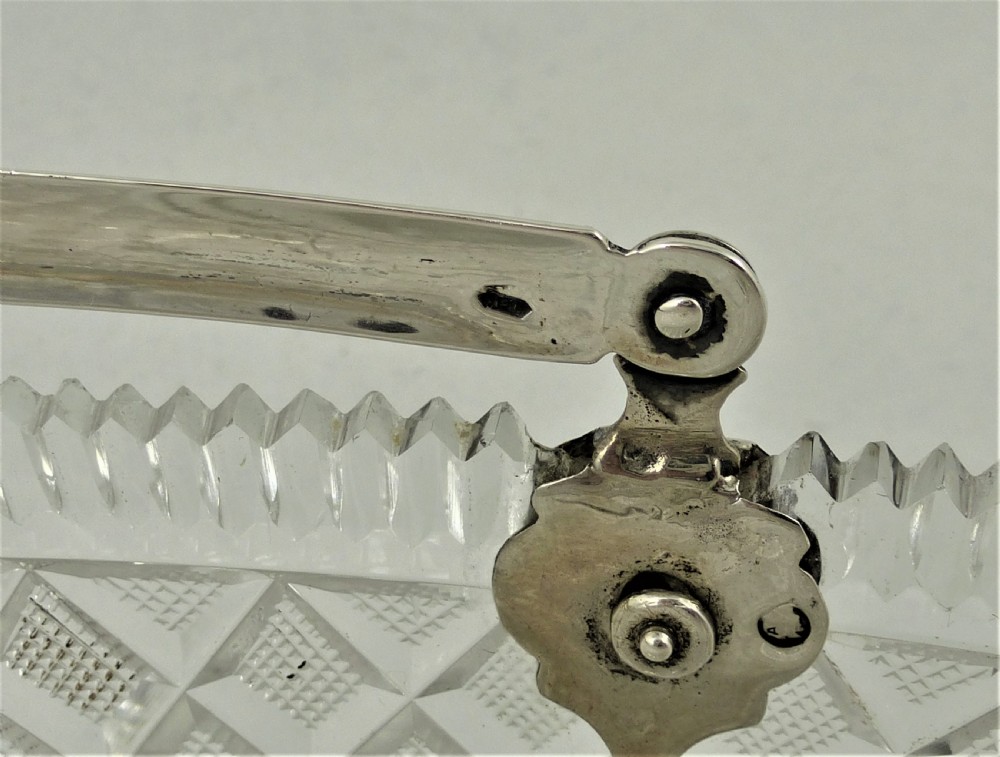 A 19th-century rectangular cut glass basket featuring diamond-patterned faceting and an arched silver swing handle attached to side mounts. View VII