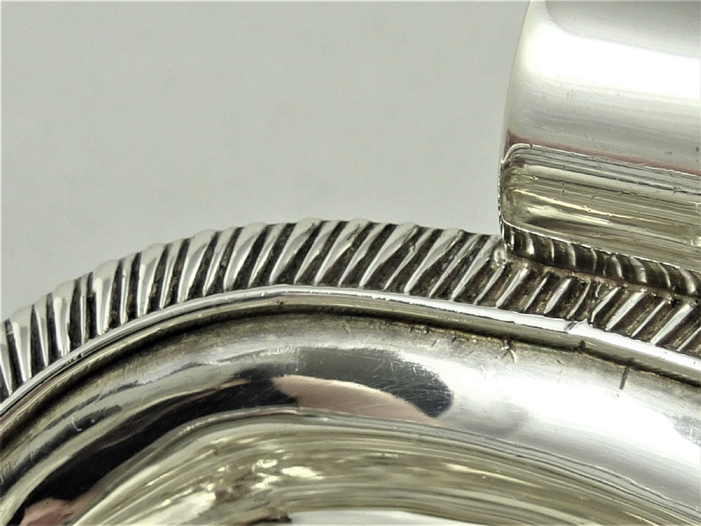 A Victorian sterling silver milk jug featuring gadrooned rim details, engraved geometric scrollwork, a shaped handle, and small ball feet. View XIV