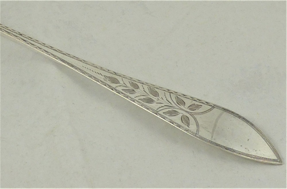 An antique Danish silver serving spoon featuring a polished oval bowl and a tapered stem decorated with bright-cut foliage engraving. View II