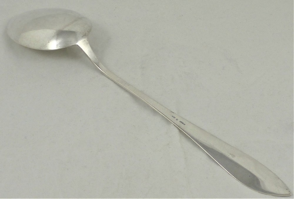 An antique Danish silver serving spoon featuring a polished oval bowl and a tapered stem decorated with bright-cut foliage engraving. View IV