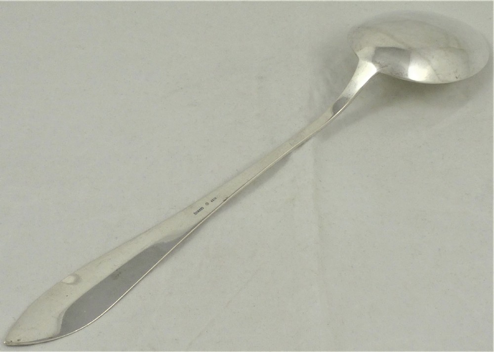An antique Danish silver serving spoon featuring a polished oval bowl and a tapered stem decorated with bright-cut foliage engraving. View VI