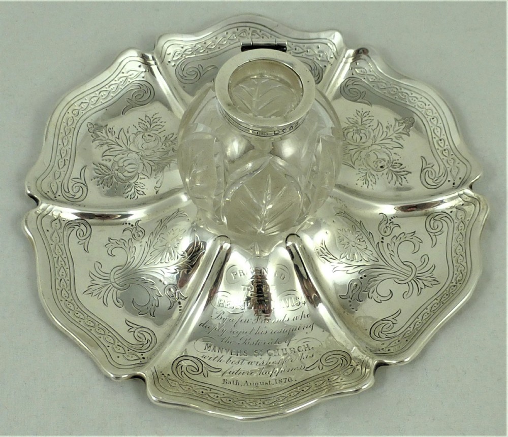 An engraved Victorian sterling silver inkstand featuring a scalloped rim tray and a central cut-glass inkwell with a silver hinged lid. View VIII