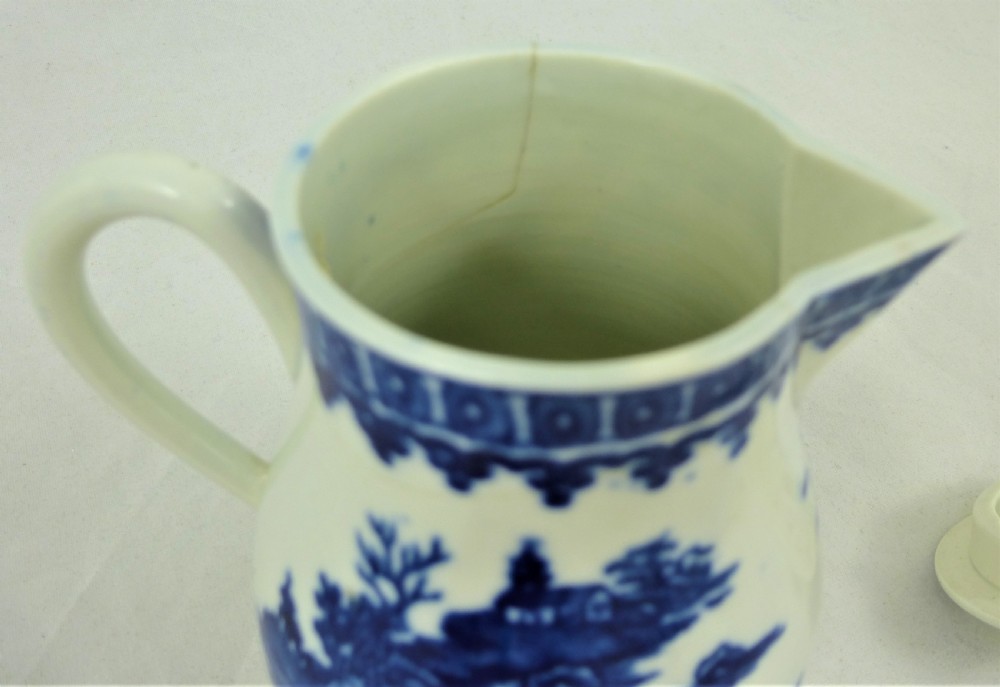 An 18th-century blue and white soft-paste porcelain sparrow beak cream jug with a floral finial lid and Chinoiserie scene. View IX