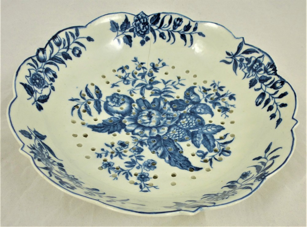 An eighteenth-century blue and white Worcester porcelain strawberry dish with pierced drainage holes resting on a matching scalloped stand. View II