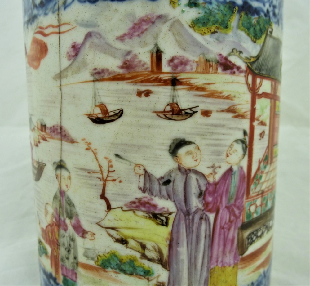 A cylindrical Chinese export porcelain mug featuring a blue dragon-shaped handle, floral enamels, and cartouches depicting figures on boats. View IX