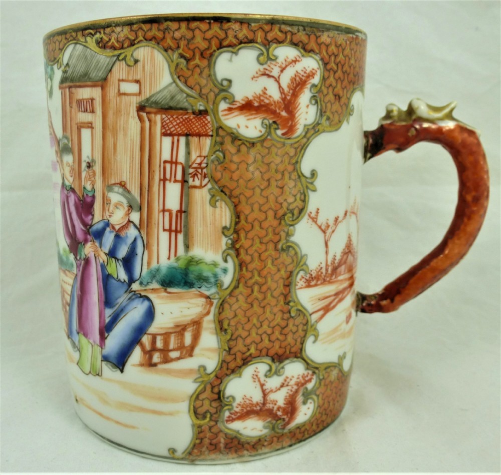 A cylindrical Chinese export porcelain mug featuring hand-painted figures inside cartouches, iron-red cell borders, and a red dragon handle.