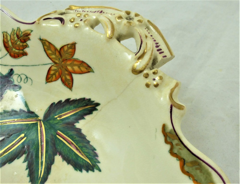 A five-piece English Rococo porcelain dessert service featuring cream-coloured shaped dishes hand-painted with green foliage, floral motifs, and gilt scalloped rims. View IV