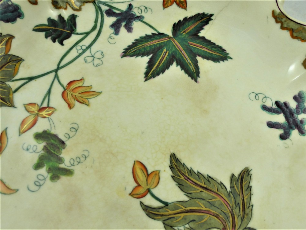 A five-piece English Rococo porcelain dessert service featuring cream-coloured shaped dishes hand-painted with green foliage, floral motifs, and gilt scalloped rims. View V