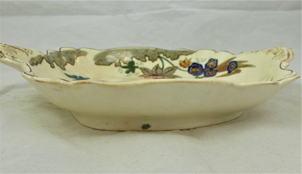 A five-piece English Rococo porcelain dessert service featuring cream-coloured shaped dishes hand-painted with green foliage, floral motifs, and gilt scalloped rims. View XI