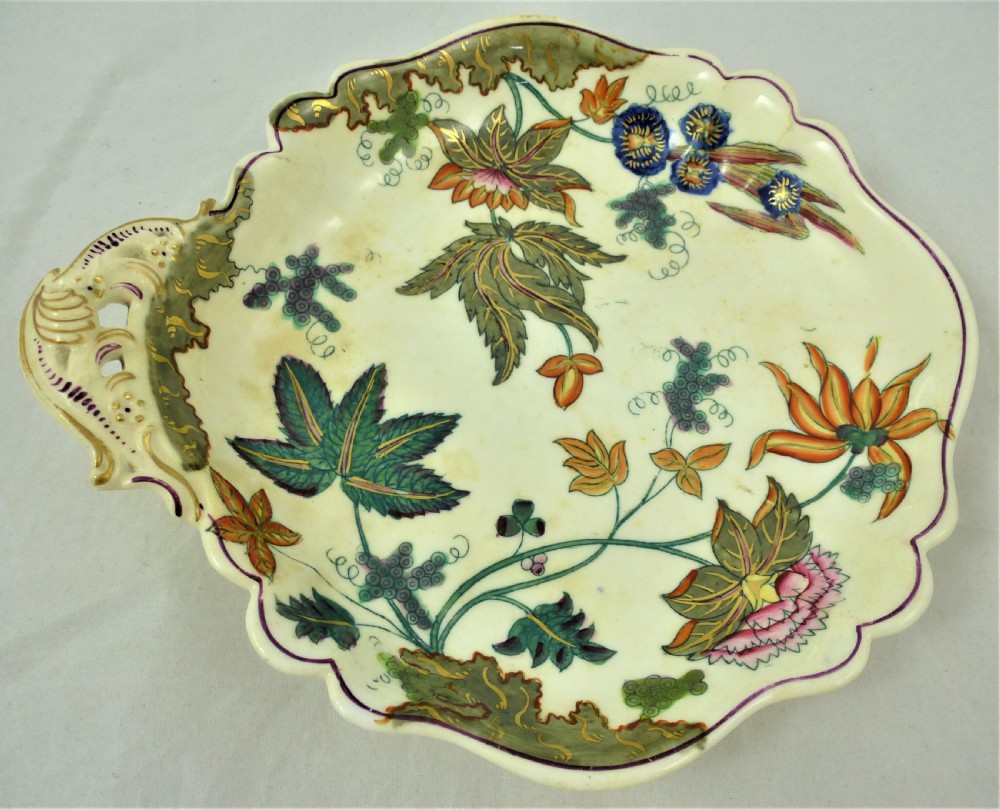 A five-piece English Rococo porcelain dessert service featuring cream-coloured shaped dishes hand-painted with green foliage, floral motifs, and gilt scalloped rims. View XIV
