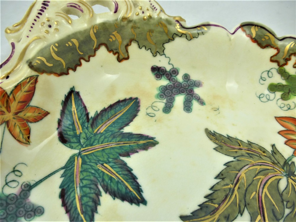 A five-piece English Rococo porcelain dessert service featuring cream-coloured shaped dishes hand-painted with green foliage, floral motifs, and gilt scalloped rims. View XV