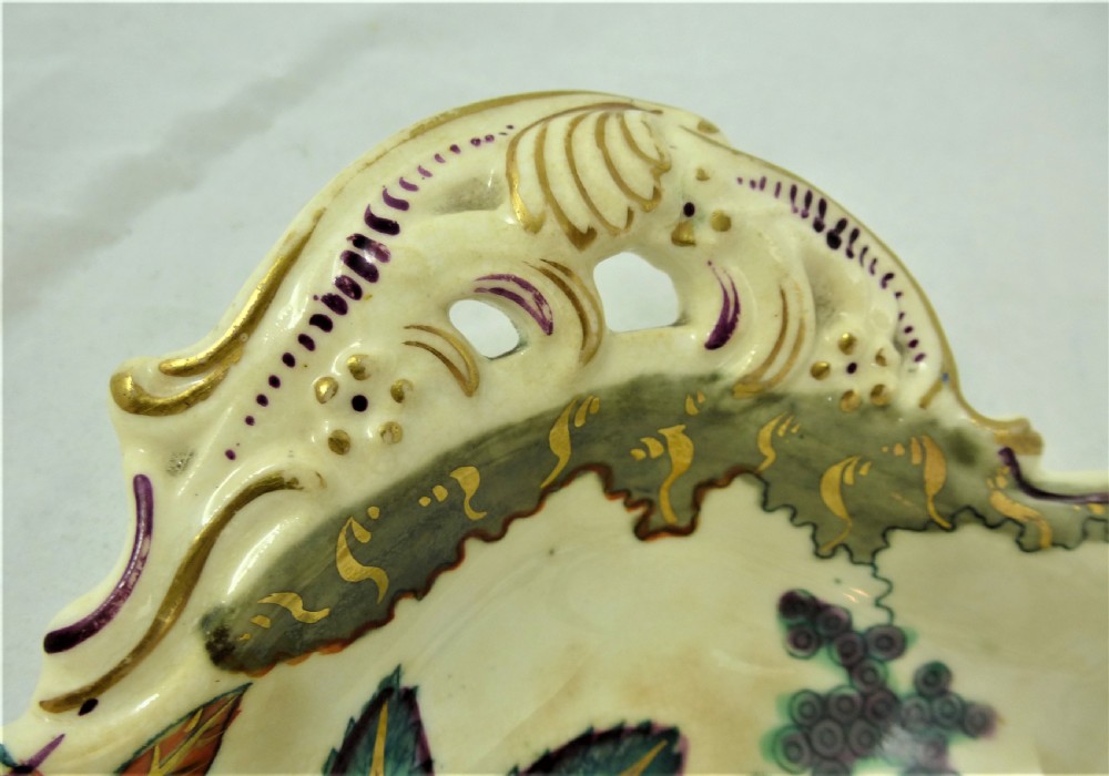 A five-piece English Rococo porcelain dessert service featuring cream-coloured shaped dishes hand-painted with green foliage, floral motifs, and gilt scalloped rims. View XVI
