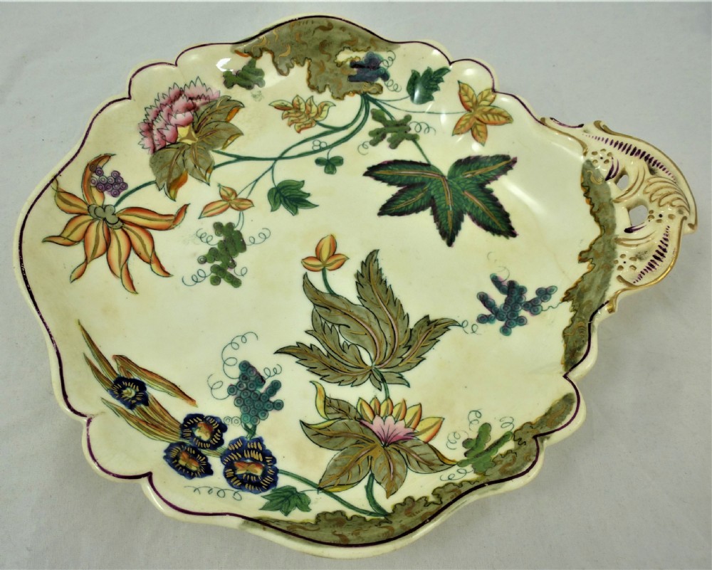 A five-piece English Rococo porcelain dessert service featuring cream-coloured shaped dishes hand-painted with green foliage, floral motifs, and gilt scalloped rims. View XX