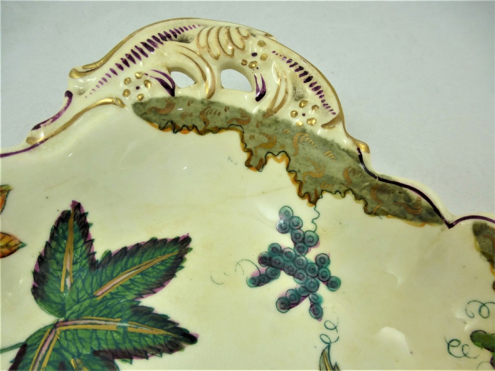 A five-piece English Rococo porcelain dessert service featuring cream-coloured shaped dishes hand-painted with green foliage, floral motifs, and gilt scalloped rims. View XXII