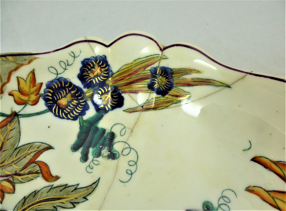 A five-piece English Rococo porcelain dessert service featuring cream-coloured shaped dishes hand-painted with green foliage, floral motifs, and gilt scalloped rims. View XXVI