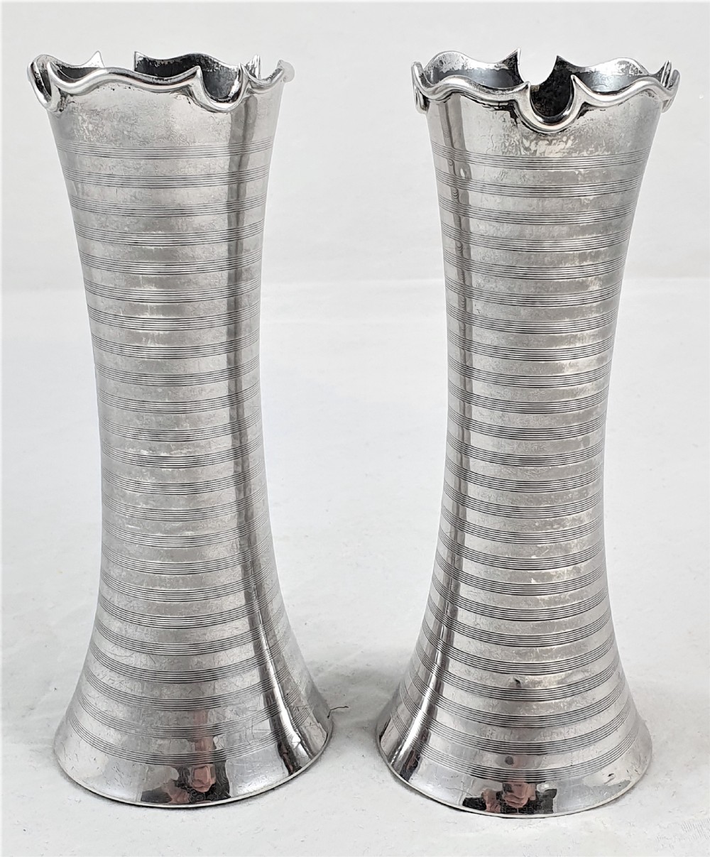 A pair of slender sterling silver trumpet vases featuring scalloped rims, horizontal reeded decoration, and central engraved floral cartouches. View V