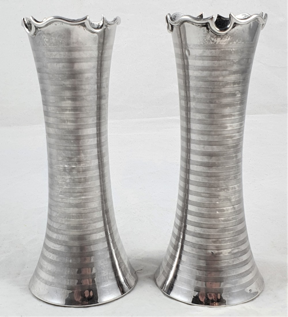 A pair of slender sterling silver trumpet vases featuring scalloped rims, horizontal reeded decoration, and central engraved floral cartouches. View VI