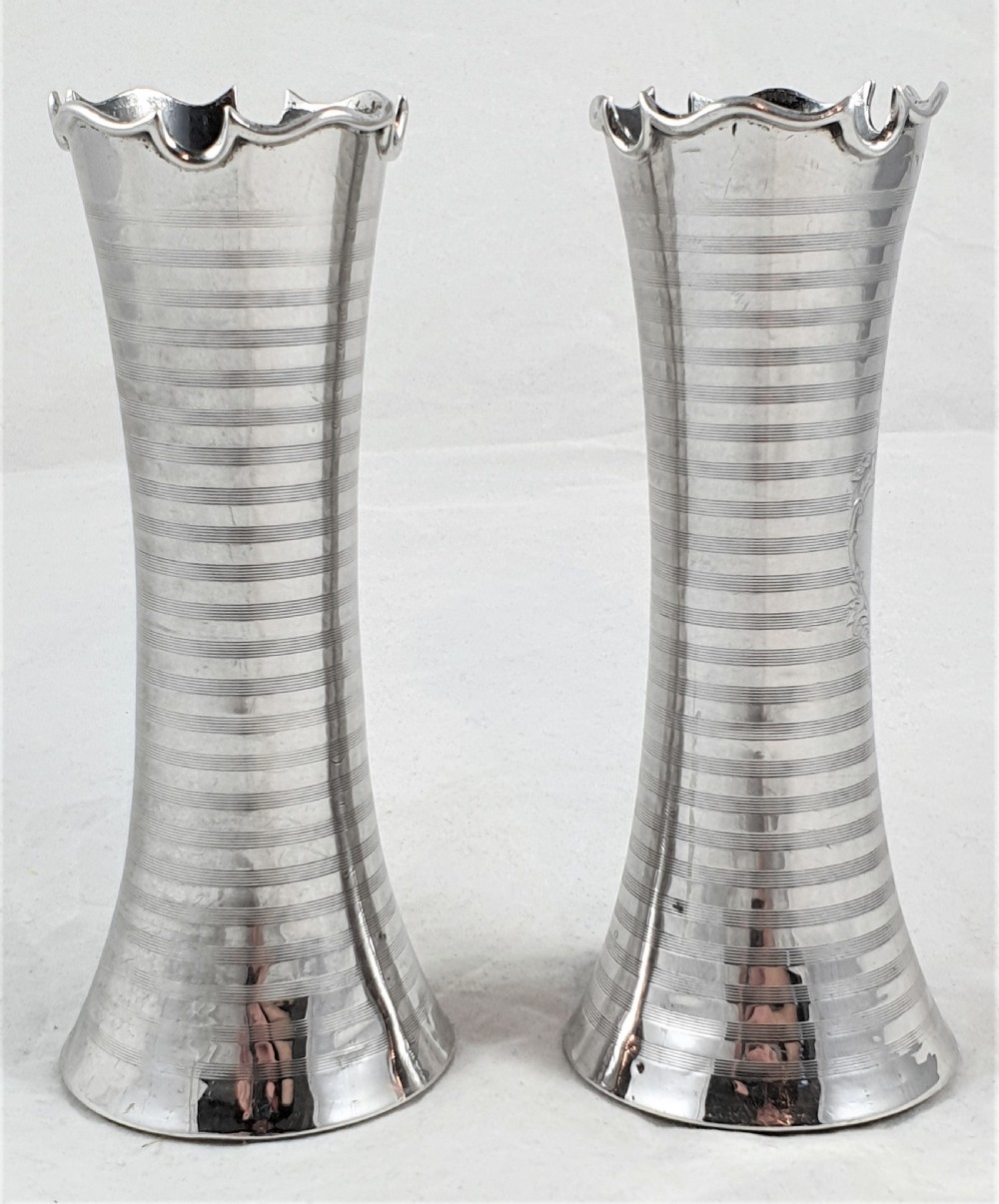 A pair of slender sterling silver trumpet vases featuring scalloped rims, horizontal reeded decoration, and central engraved floral cartouches. View VII