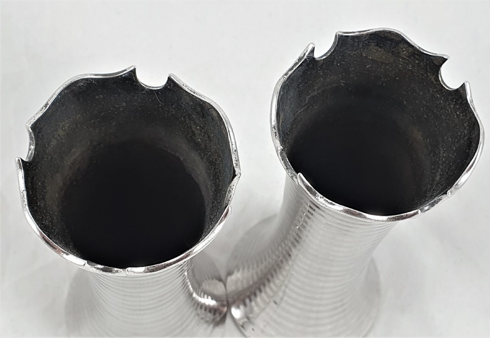 A pair of slender sterling silver trumpet vases featuring scalloped rims, horizontal reeded decoration, and central engraved floral cartouches. View VIII