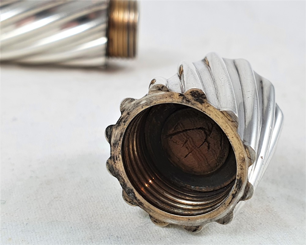 A Victorian sterling silver double-ended scent bottle with spiral fluted decoration, featuring a hinged lid with a glass stopper on one side and a detached screw cap on the other. View VIII