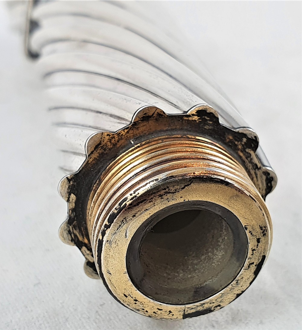 A Victorian sterling silver double-ended scent bottle with spiral fluted decoration, featuring a hinged lid with a glass stopper on one side and a detached screw cap on the other. View IX