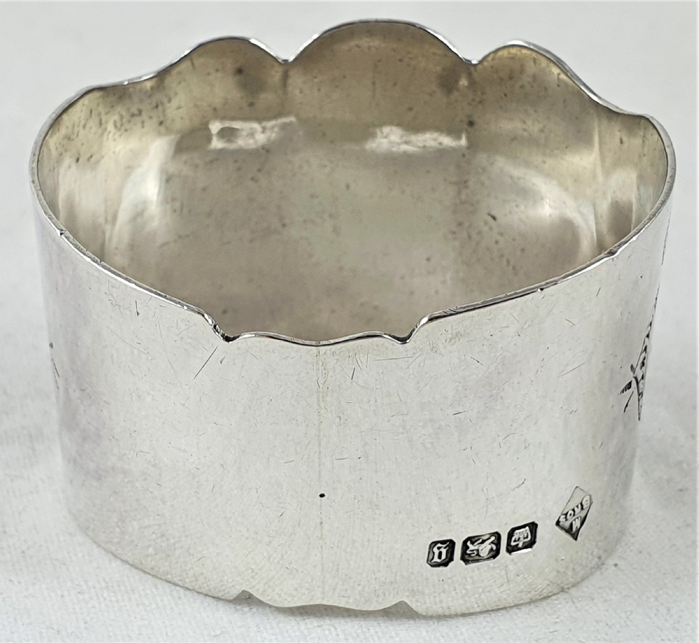 A Victorian silver napkin ring featuring a scalloped rim, detailed scroll engraving, and a central circular cartouche with a monogram. View III