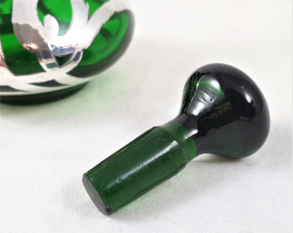 An Art Nouveau green glass scent bottle featuring silver overlay scrollwork and a fitted dark stopper. View VI