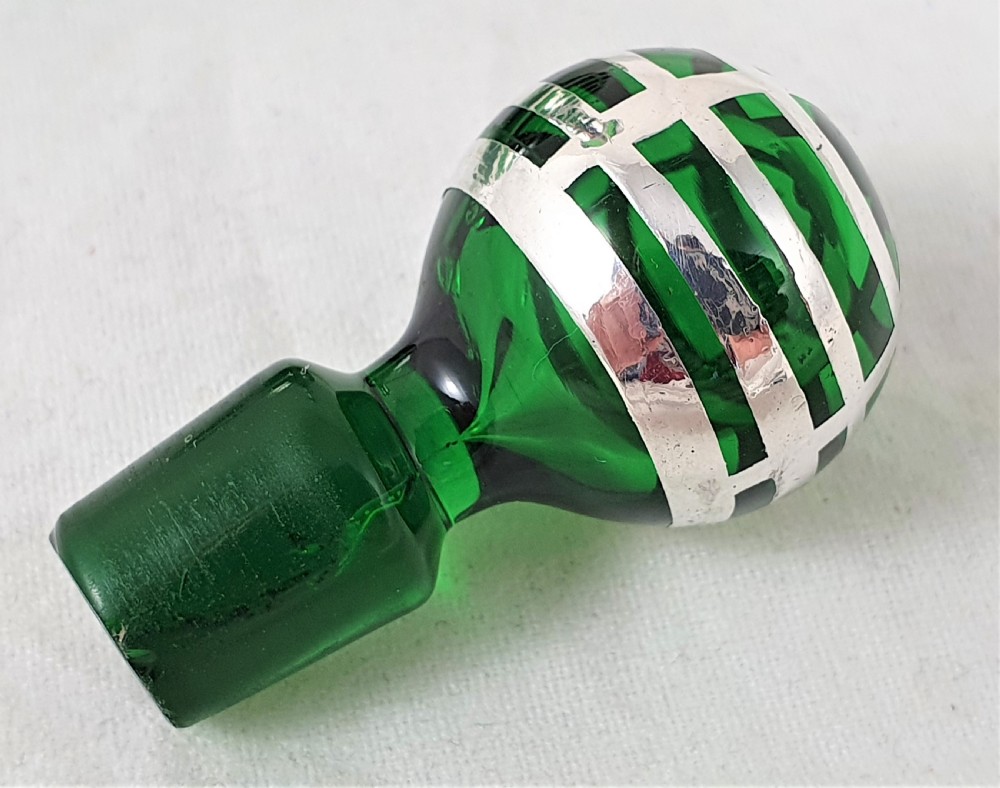 An emerald green glass perfume bottle featuring silver overlay in geometric and linear patterns with a matching silver-covered globe stopper. View VI