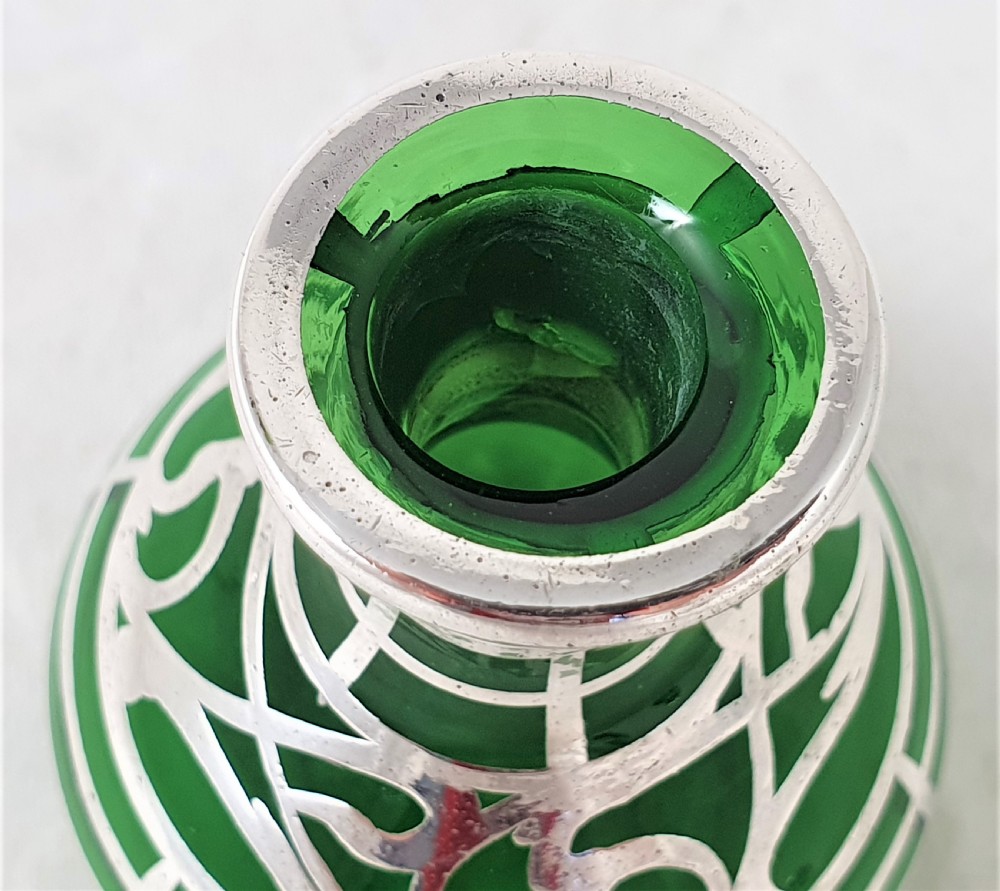An emerald green glass perfume bottle featuring silver overlay in geometric and linear patterns with a matching silver-covered globe stopper. View VII