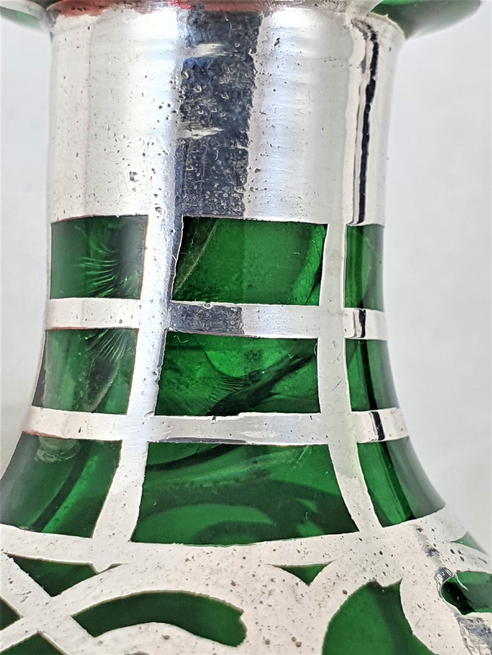 An emerald green glass perfume bottle featuring silver overlay in geometric and linear patterns with a matching silver-covered globe stopper. View XI