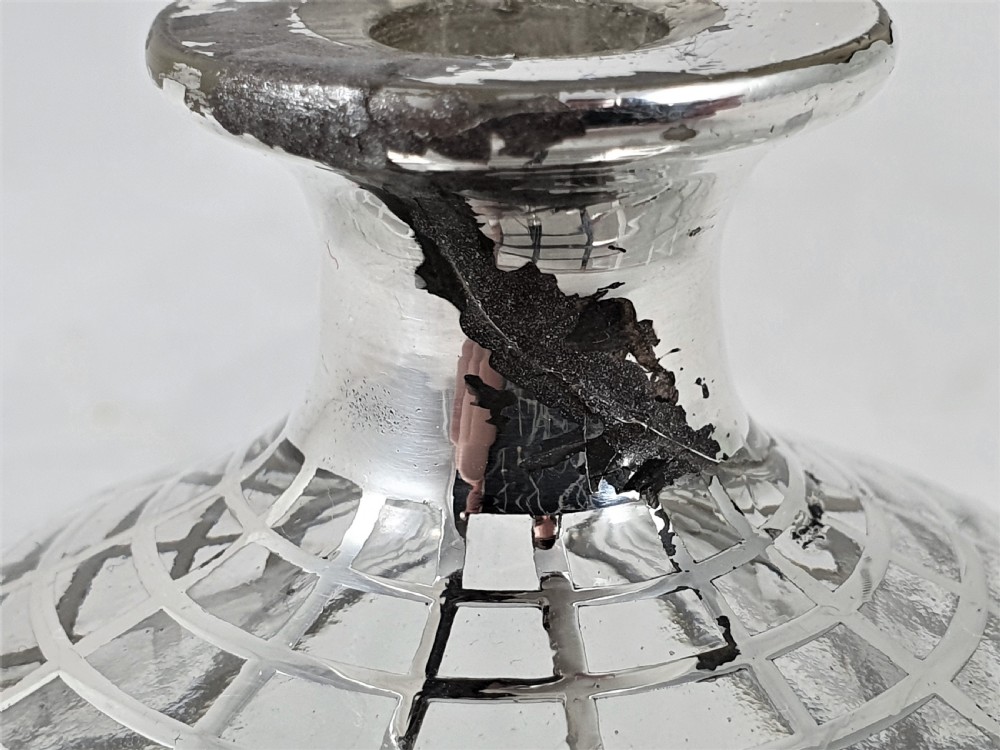 A round clear glass perfume bottle featuring a grid pattern silver overlay and a spherical silver stopper. View X