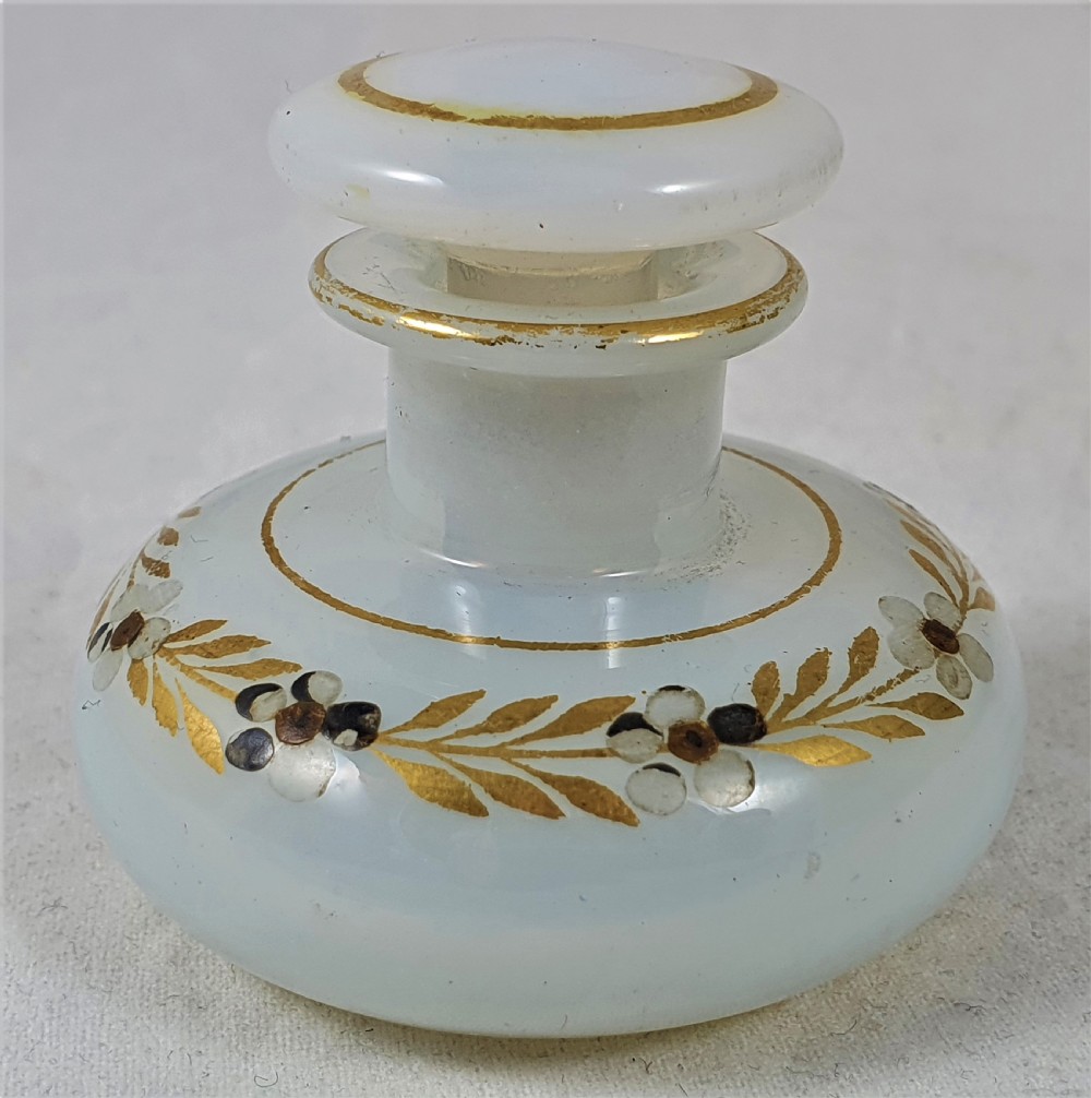 A small squat opalescent glass scent bottle featuring hand-painted gilded floral garlands around the body and a matching disc stopper. View II