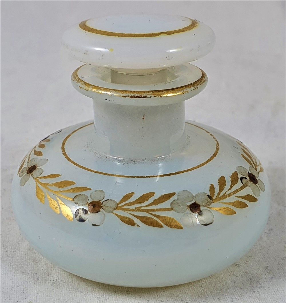 A small squat opalescent glass scent bottle featuring hand-painted gilded floral garlands around the body and a matching disc stopper. View III