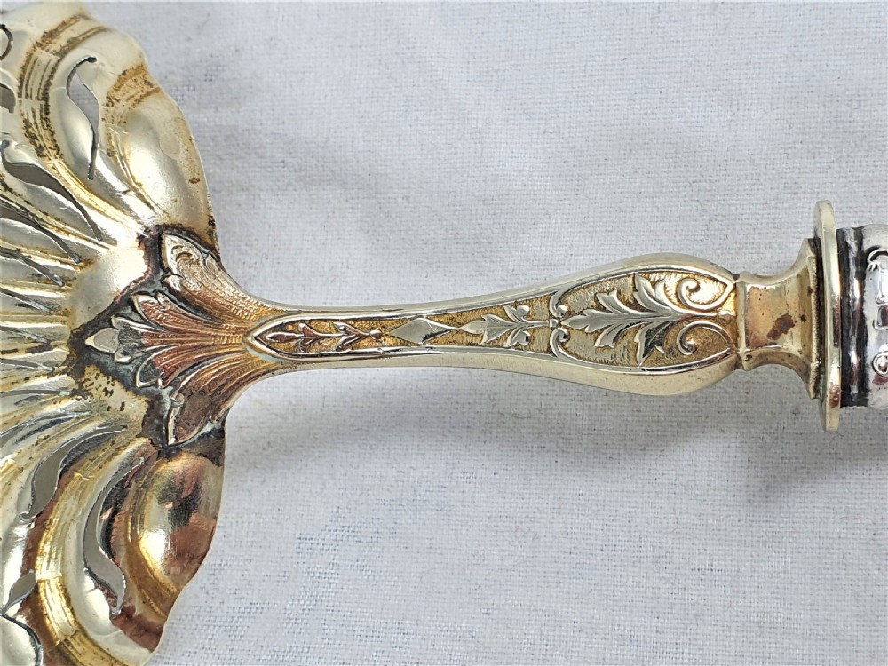 A nineteenth-century French silver-plated sugar sifter featuring a pierced shell-shaped gilded bowl and relief handle, presented in a dark fitted case. View VIII