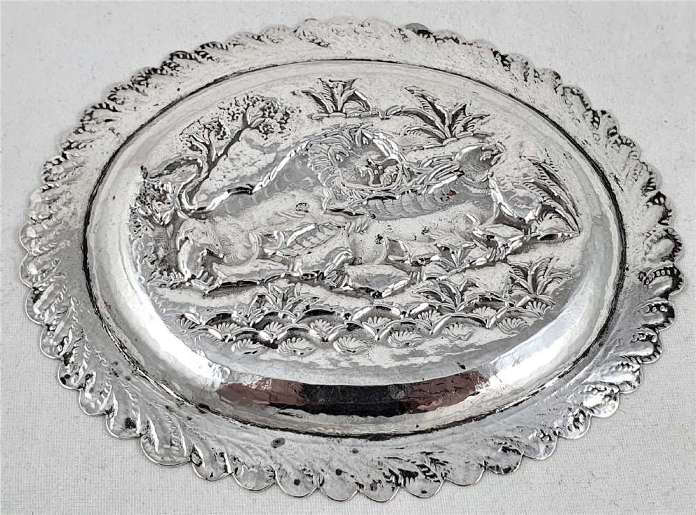 An oval silver dish featuring a chased repousse hunting scene in relief with a leaf pattern border. View V