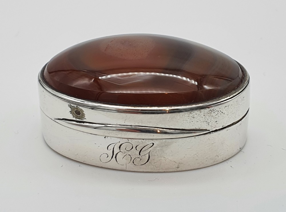 A Georgian oval silver vinaigrette featuring a smooth brown agate top and engraved script monogram on the silver collar. View II