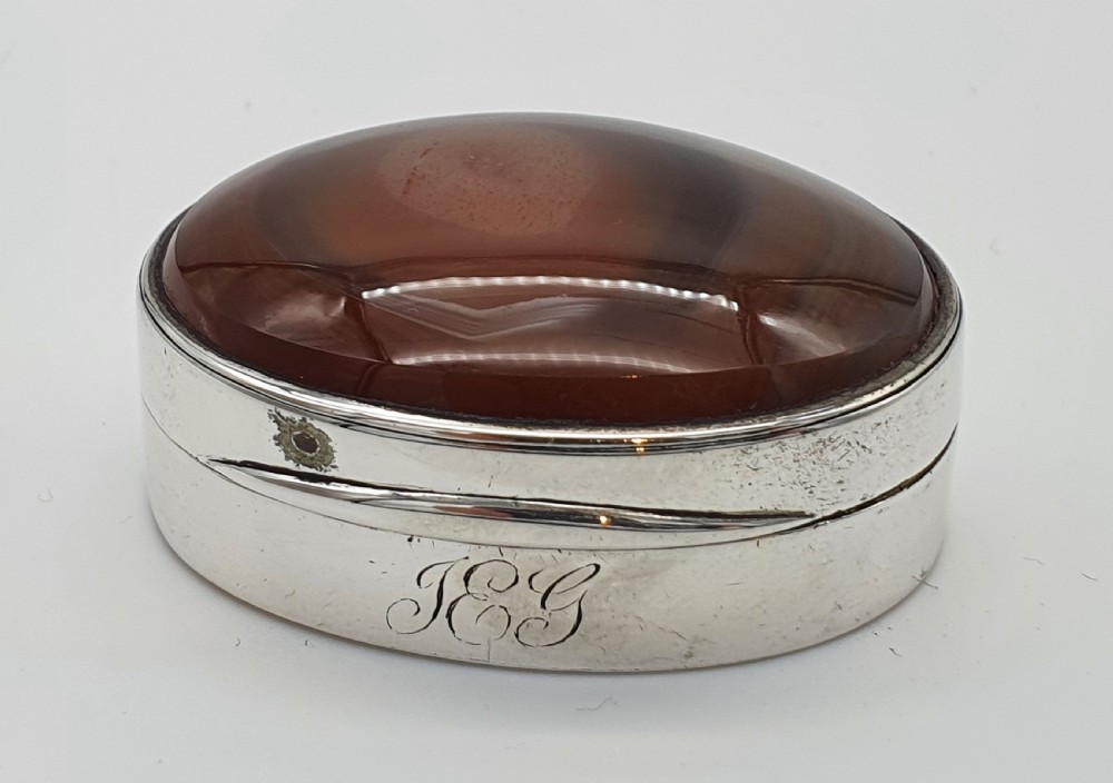 A Georgian oval silver vinaigrette featuring a smooth brown agate top and engraved script monogram on the silver collar. View III