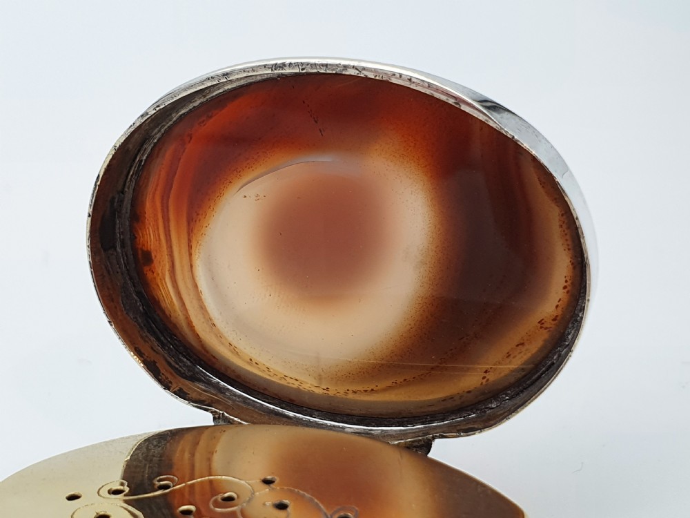 A Georgian oval silver vinaigrette featuring a smooth brown agate top and engraved script monogram on the silver collar. View VI
