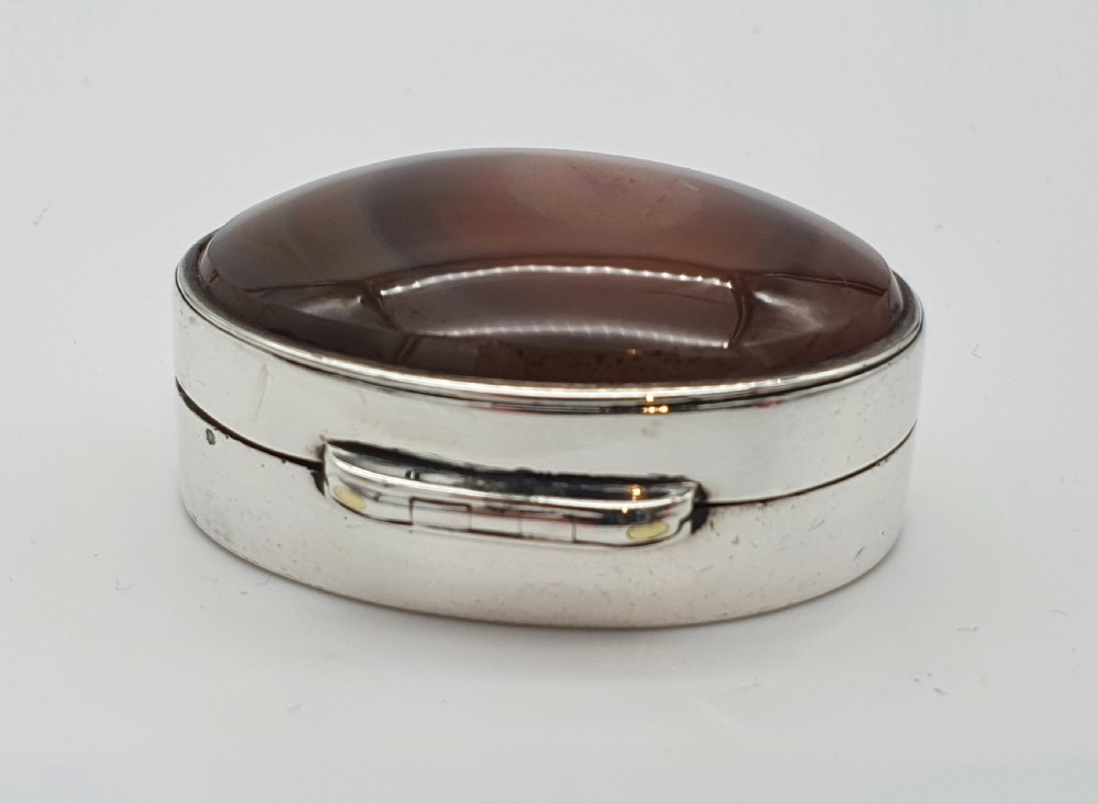 A Georgian oval silver vinaigrette featuring a smooth brown agate top and engraved script monogram on the silver collar. View VII