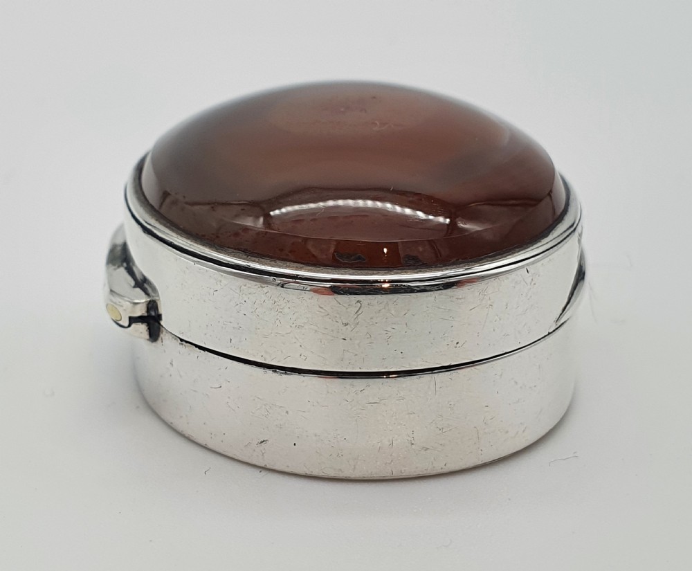 A Georgian oval silver vinaigrette featuring a smooth brown agate top and engraved script monogram on the silver collar. View VIII